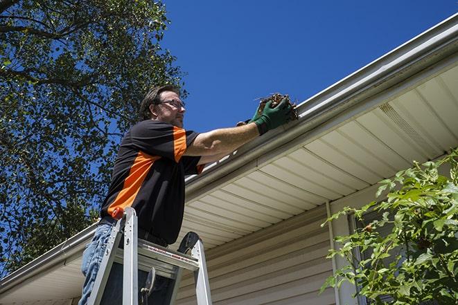 a professional repairman fixing a damaged gutter in Alton